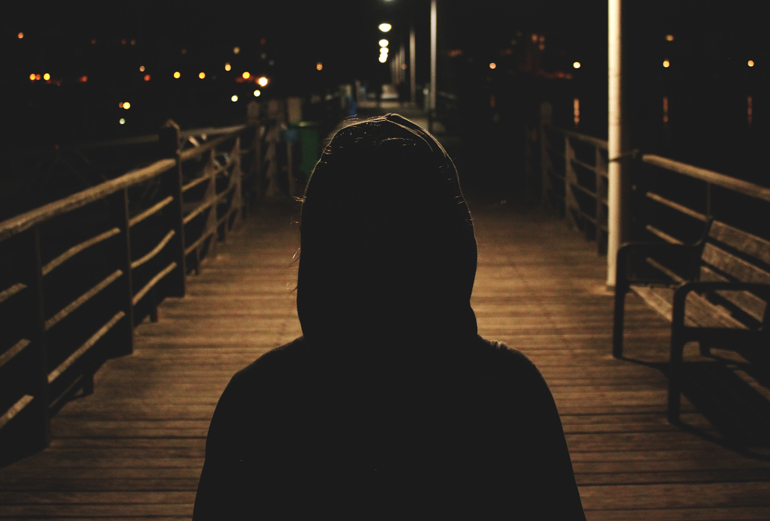 в капюшоне на темной пристани