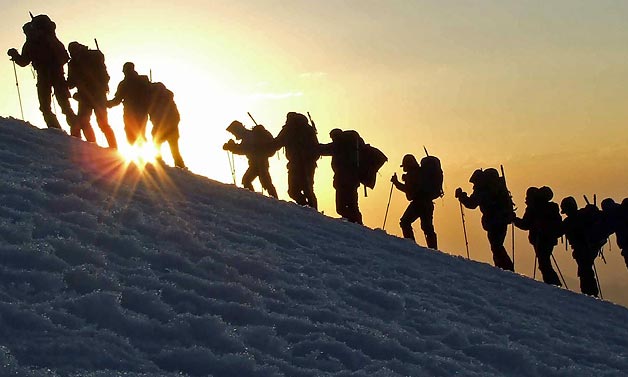люди идут на закате по склону