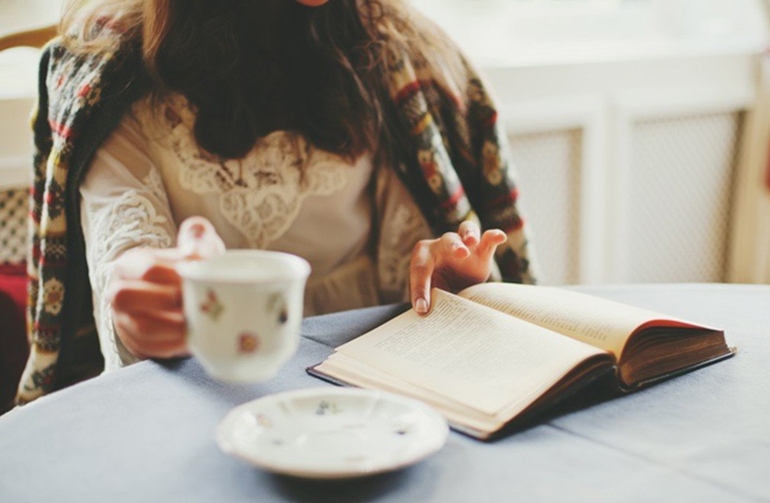 за столом с книгой и чашкой